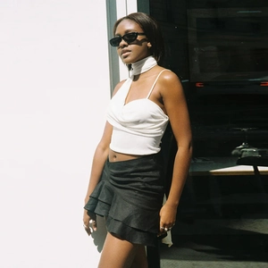 Detail of white halter neck crop top with tie-up straps and tiered black ruffled skirt