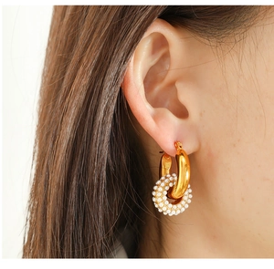 Close-up of dual-ring earrings with polished gold hoop and interlocking pearl circle