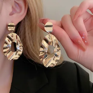 Irregular textured gold oval hoop earrings with a crumpled metal finish and geometric design