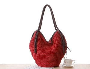 Détail du sac à main en corde de papier tressée rouge avec doubles anses brunes et longs glands