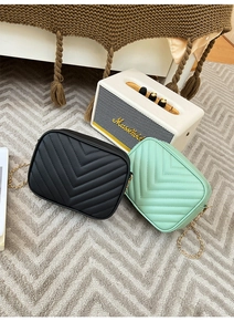 Detail of V-quilted camera bags in black and mint green with elegant gold chain straps