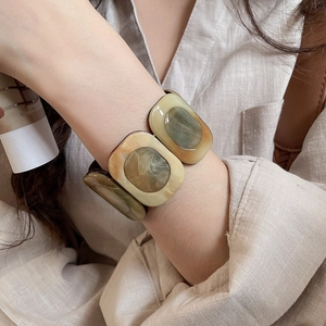 Macro detail of a wide resin square bracelet with amber and green marble texture