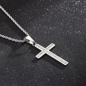 Macro shot of silver stainless steel cross pendant with diamond inlay on black background