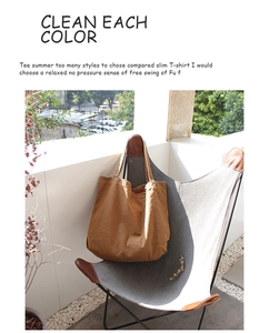 Detailed view of a brown vintage canvas tote bag placed on a grey leisure chair