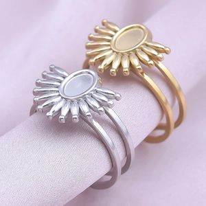 Macro view of gold and silver sunburst oval ring settings on soft pink silk background