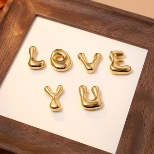 Close-up of 18K gold-plated 3D bubble letter pendants spelling LOVE YOU on white card