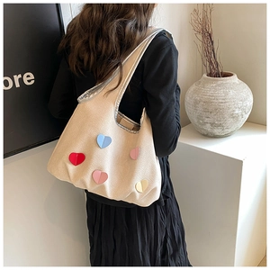 Gros plan du sac fourre-tout crème avec écussons cœurs colorés et large bandoulière