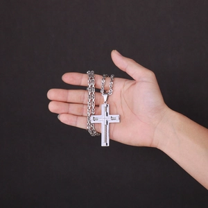 Close-up of a silver cross pendant on a double-layered stainless steel necklace