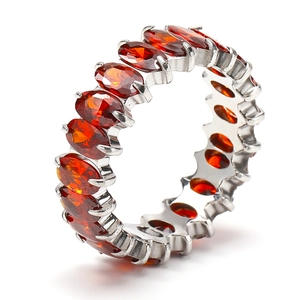 Detail view of silver eternity band featuring oval-cut orange-red zircon gemstones