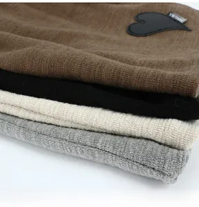 Close-up of ribbed knit fabric texture with leather heart patch and small brand label