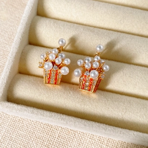 Detailed close-up of gold plated popcorn earrings with pearls and red rhinestones