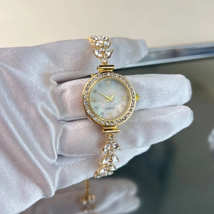 Detail der goldenen Quarzuhr mit Blatt-Armband, Strasssteinen und Perlmutt-Zifferblatt
