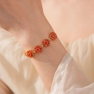 Macro detail of gold-plated flower bracelet with five faceted orange zircon floral charms