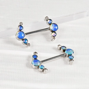 Macro shot of silver stainless steel nipple rings with iridescent blue floral stone inlay