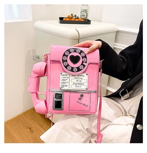 Detail shot of a creative pink retro telephone crossbody bag with glossy patent leather finish
