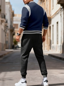 Side view of a navy blue patchwork baseball jacket and black jogger pants on street