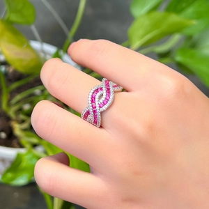Macro shot of silver crisscross ring with ruby and white gemstones on a finger