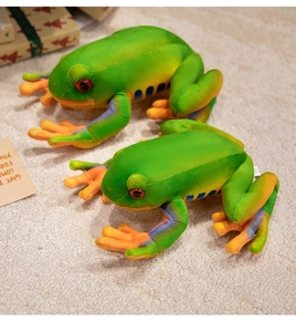 Detail of red-eyed tree frog plush toys with green fur and orange limbs on a soft carpet
