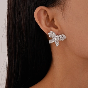 Detailed close-up of a silver butterfly earring with zircons on a female model