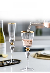 Close-up of pouring rosé wine into a gold-rimmed crystal champagne glass with bead detail