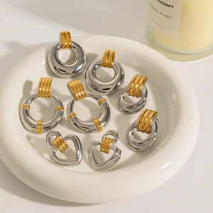 Two-tone stainless steel hoop earrings set with gold and silver accents on ceramic tray