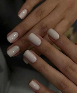 Close-up of glossy cream white press-on nails in short square oval shape for daily wear