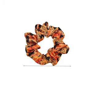Detail of Halloween hair scrunchie with orange pumpkin spider web pattern and trick text