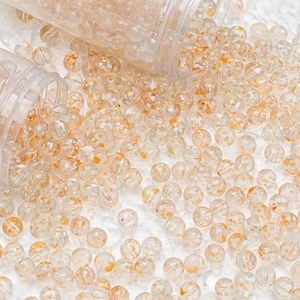 Close-up of translucent orange floral glass beads scattered from clear containers