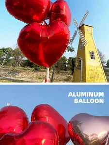 Close-up of red and rose gold 18-inch heart-shaped foil balloons against a blue sky