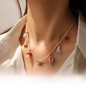 Detail of woven necklace with cherry and ceramic flower pendants on model with white shirt