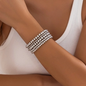 Close-up of layered silver bead bracelet with heart pendant on model wrist