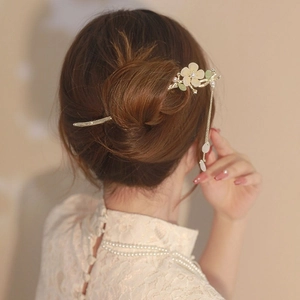 Vue arrière d'un pic à cheveux muguet avec pompons perles dans un chignon chic