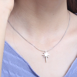 Close-up of woman wearing a silver star pendant with rhinestones on a snake chain