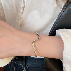 Macro shot of polished silver irregular wavy cuff bracelet with minimalist fold texture