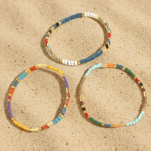 Bohemian Tila beaded bracelets set for summer beach wear on natural sand background