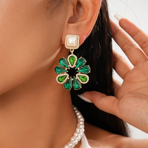Close-up of vintage flower earrings with green teardrop crystals and square pearls