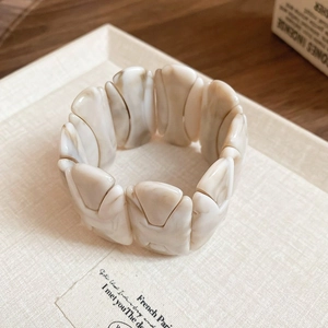 Macro detail of H-shaped modular acetate bangle with ivory marble texture