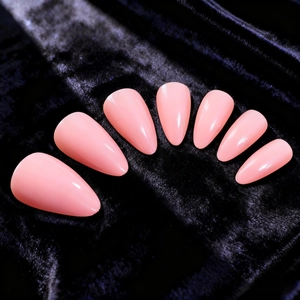 Glossy light pink press-on nails in long almond shape displayed on black velvet background