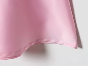 Detailed view of pink satin fabric texture and high-quality stitching on a lace camisole skirt
