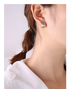 Close-up of minimalist matte silver C-shaped hoop earring worn by a model