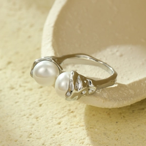 Detail of molten texture silver ring with two white pearls on a ceramic surface