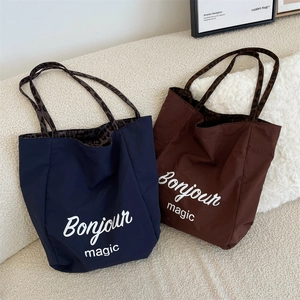 Close-up of stylish tote bags with Bonjour magic print and trendy leopard handles