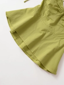 Dettaglio del camisole verde erba che mostra le cuciture dell'orlo e il tessuto
