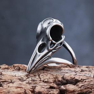 Close-up of vintage Viking crow skull ring in aged silver finish on a rustic bark base