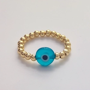 Macro detail of elastic beaded ring with golden spheres and blue Evil Eye charm