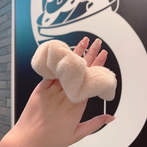 Soft faux fur scrunchie in light pink, plush oversized hair tie worn on a hand