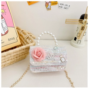 Detailed shot of tweed girl's handbag with pearl handle, pink rose, and gold chain strap