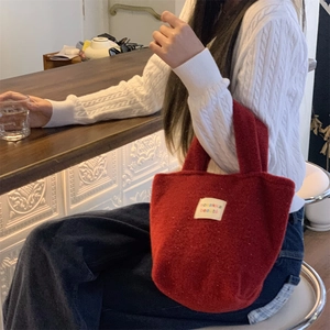 Detail of a small red felt handbag with decorative patch on a wooden counter top