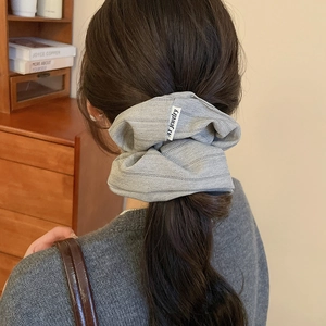 Detail of light grey fabric scrunchie with twill texture worn on long brown hair