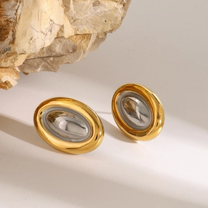 Détail de boucles d'oreilles ovales bicolores or 18k et argent sur fond de pierre naturelle